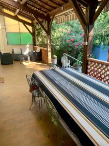 a covered patio with a couch and chairs and a table at La Bigotière avec clim et jardin in Arles