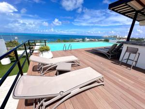 a deck with chairs and a swimming pool at New apartment Neen in Cancún