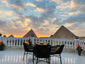 un tavolo e sedie su un balcone con piramidi di New Scarab Pyramids View a Il Cairo