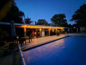 a swimming pool in front of a house at night at Ham Annex met privé jacuzzi in Almelo