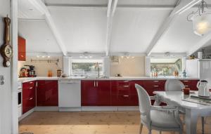 una cocina con armarios rojos y una mesa blanca en Pet Friendly Home In Blokhus With Wifi, en Blokhus 17 fotos más
