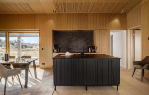 a kitchen with a black island in a room with a table at 6 Bedroom Cozy Home In Løkken in Løkken