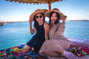 two women sitting next to the water on a boat at Uros mojsa lodge in Puno