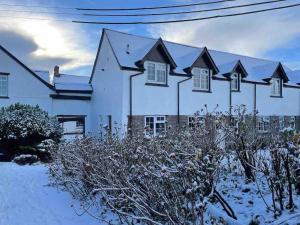 a white house with snow in front of it at Marigold Cottage in West Down +27 photos