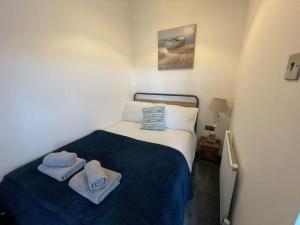 a small bedroom with a bed with towels on it at Marigold Cottage in West Down