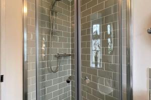 a shower with a glass door in a bathroom at Marigold Cottage in West Down