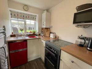 a small kitchen with a stove and a sink at Marigold Cottage in West Down