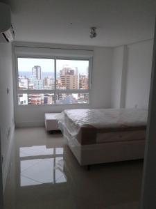a bedroom with a bed and a large window at Apartamento no 20 piso com 90m2 e linda vista in Torres