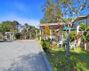 a house with two white chairs in the yard at Bide-A-Wee Inn and Cottages in Pacific Grove