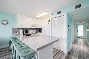 a kitchen with white cabinets and a counter with stools at Paradise Palms Ocean Pointe 1206 in Key Largo
