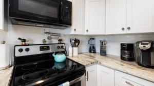 une cuisine avec une cuisinière noire et un micro-ondes dans l'établissement Sea View and Sunrise Top Floor Ocean Pointe 2412, à Key Largo 50 autres photos