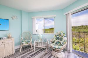a living room with two chairs and a balcony at Paradise Palms Ocean Pointe 1206 in Key Largo