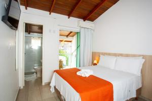a bedroom with a bed with an orange blanket at Pousada Doce Encanto in Florianópolis