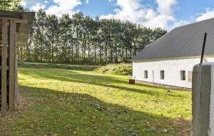 a white barn with a grass field next to it at Beautiful Home In Grenaa With Wifi in Grenå +3 photos