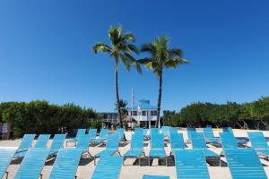 una fila de tumbonas azules en una playa con palmeras en Sunshine Paradise Key Largo Ocean Pointe 4402, en Cayo Largo