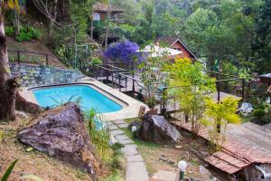 einen Pool in einem Garten neben einem Haus in der Unterkunft Pousada Moriá in Visconde De Maua
