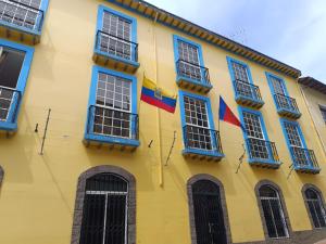 un edificio giallo con finestre blu e bandiere di Quito Basecamp - Adventure Hostel a Quito
