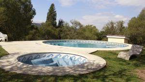 a swimming pool in the grass with a bench around it at Hostel El Rincon in Villa General Belgrano