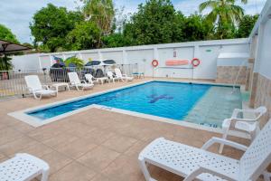 a swimming pool with white chairs at Hotel Villa Paraiso in Villavieja