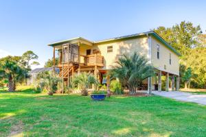 a large yellow house with a balcony and a yard at Waterfront Gulf Coast Home with Outdoor Oasis! in Gautier