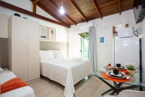 a bedroom with a white bed and a glass table at Pousada Doce Encanto in Florianópolis