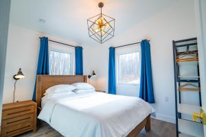 a bedroom with a bed with blue curtains and a chandelier at Shangri-La Cottages in Burntcoat
