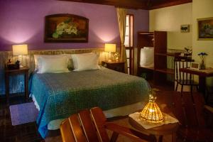 ein Schlafzimmer mit einem Bett und einer lila Wand in der Unterkunft Pousada Moriá in Visconde De Maua + 147 Fotos