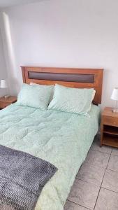 a bed with a wooden headboard and two night stands at Portada VIP in La Chimba