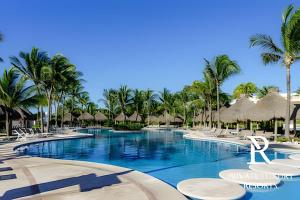 a resort swimming pool with palm trees and umbrellas at The Grand Luxxe Res Two Bedroom Loft- Riviera Maya in Nuevo Vallarta
