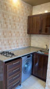 a kitchen with a washing machine and a sink at Izz AlDin Tamimi St شقة مفروش سوبر ديلوكس الجبيهة in Ţāb Kirā‘