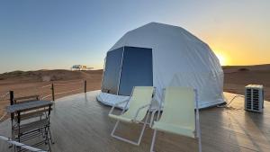 una tenda nel deserto con sedie e tavolo di Starry Domes Desert Camp a Badīyah