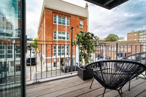 a balcony with two chairs and a plant at Chic property near Tower Hill with a gym in London