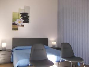 two chairs in front of a bed in a bedroom at Maria Teresa's Large Open space indipendent in Cardedu