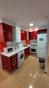 a kitchen with red cabinets and a washing machine at Playa, relax y parking público cerca - Ideal parejas in Cullera
