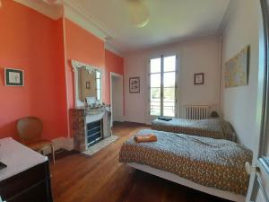 a bedroom with orange walls and two beds and a fireplace at Aile Château La Chapelle du Bois des Faulx in La Chapelle-du-Bois-des-Faulx