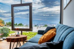 a living room with a blue couch and a large window at Hotel Frost in Maribor
