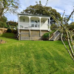 a white house with a porch on a lawn at Hahei Cottages - Willow or Kauri in Hahei +11 photos