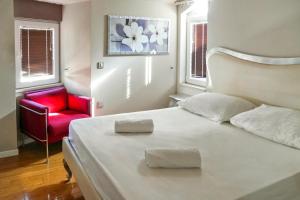 a bedroom with a white bed and a red chair at Kristal Paris Resort in Novalja +97 photos