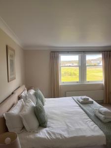 a bedroom with a large white bed with a window at Golf Court View, Elie in Elie +23 photos