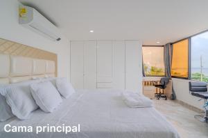 a white bedroom with a large bed and a desk at lujoso apartamento familiar frente al mar in Cartagena de Indias