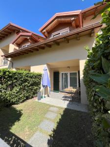 a house with an umbrella and a table and chairs at Casa da Matti in Gravedona