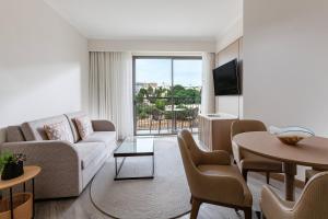 a living room with a couch and a tv and a table at Malta Marriott Resort & Spa in St. Julianʼs