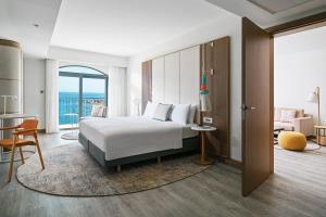 a hotel room with a bed and a living room at Malta Marriott Resort & Spa in St. Julianʼs