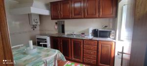 a kitchen with wooden cabinets and a table with a microwave at Casa da Torre in Penela
