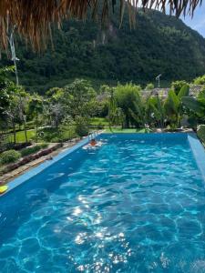a large blue swimming pool with a mountain in the background at Bó Bun Homestay Mộc Châu in Mộc Châu +26 photos