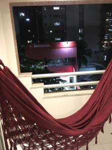 a hammock in front of a window in a building at Poucos passos do mar na Praia da Costa in Vila Velha