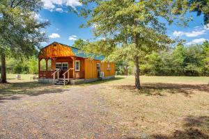a cabin in a field with a tree at Plantersville Cabin on 50 Acres with Pond and Fire Pit in Magnolia