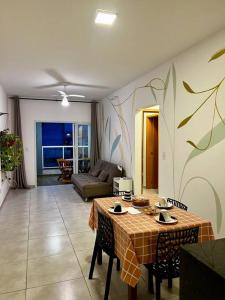 a living room with a table and a couch at Apê Jardins 212 - Piscina, Churrasqueira, 2 Quartos a 600m da Orla Central in Ubatuba