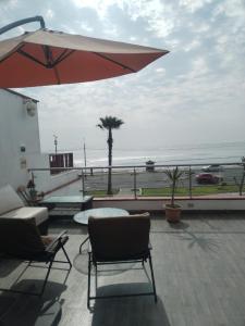 a patio with chairs and an umbrella and the ocean at Departamento con HERMOSA VISTA AL PACÍFICO in Huanchaco