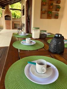 a wooden table with green plates and cups on it at Casa Becker - Praia Seca in Araruama